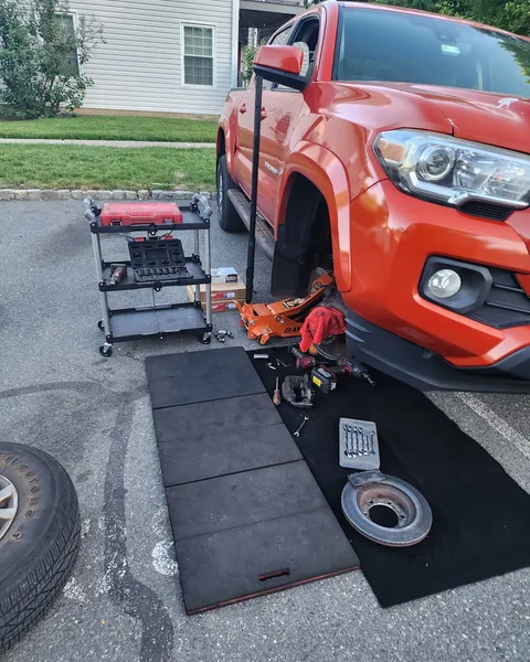 Toyota Tacoma on a jack, wheel off, in a parking lot